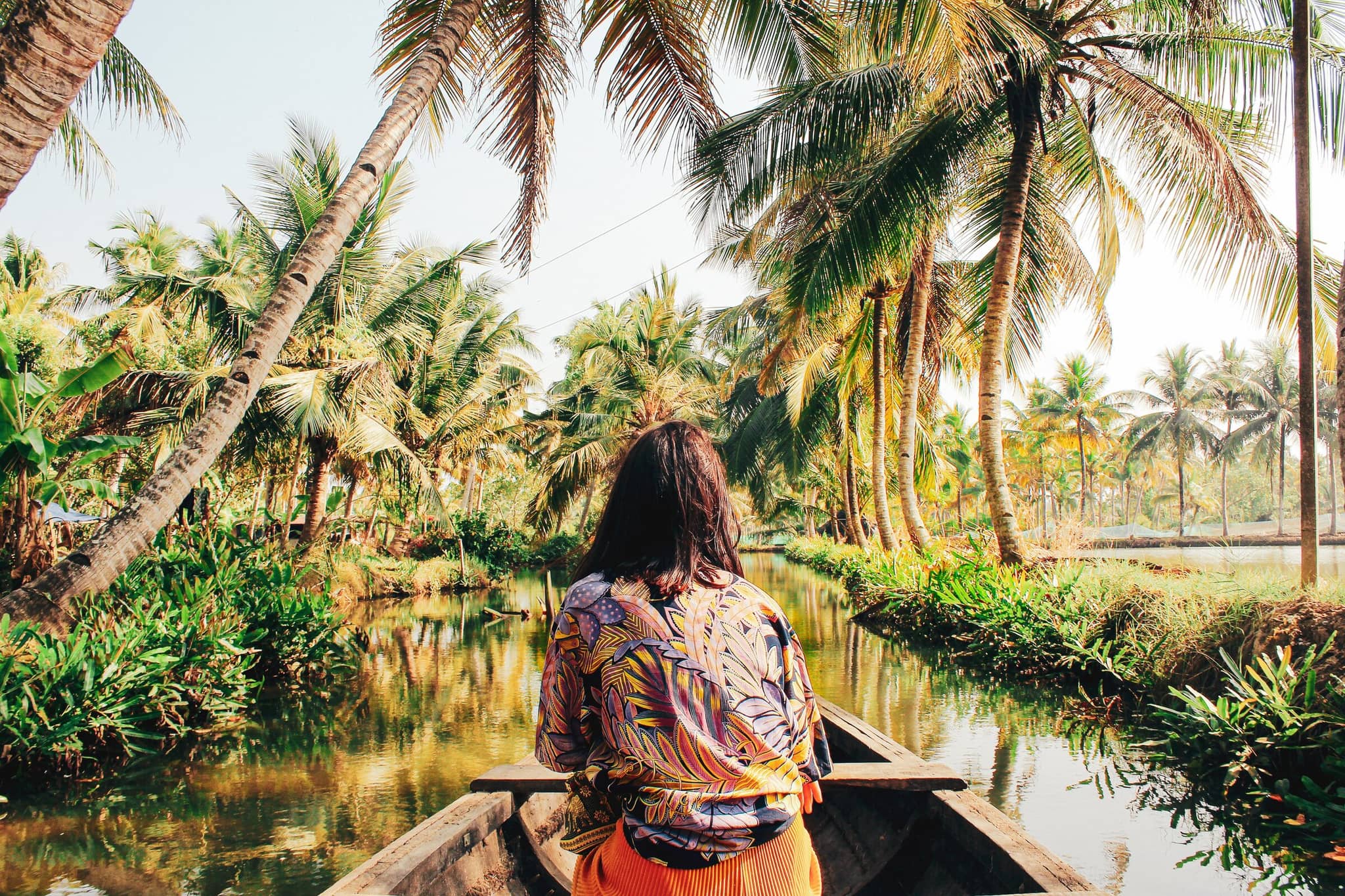 Woman exploring lush tropical jungle by boat, representing immersive luxury adventure travel experience.