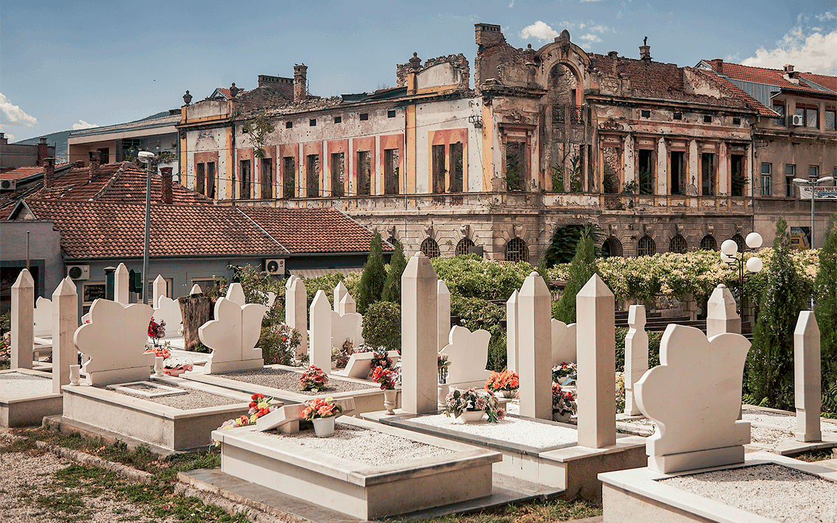 Cemetery with broken house in the background, Mostar, Bosnia and Herzegovina.