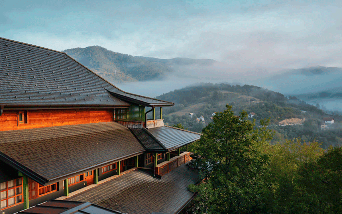 Exterior view of hotel Mecavnik in Drvengrad with early morning fog, Serbia
